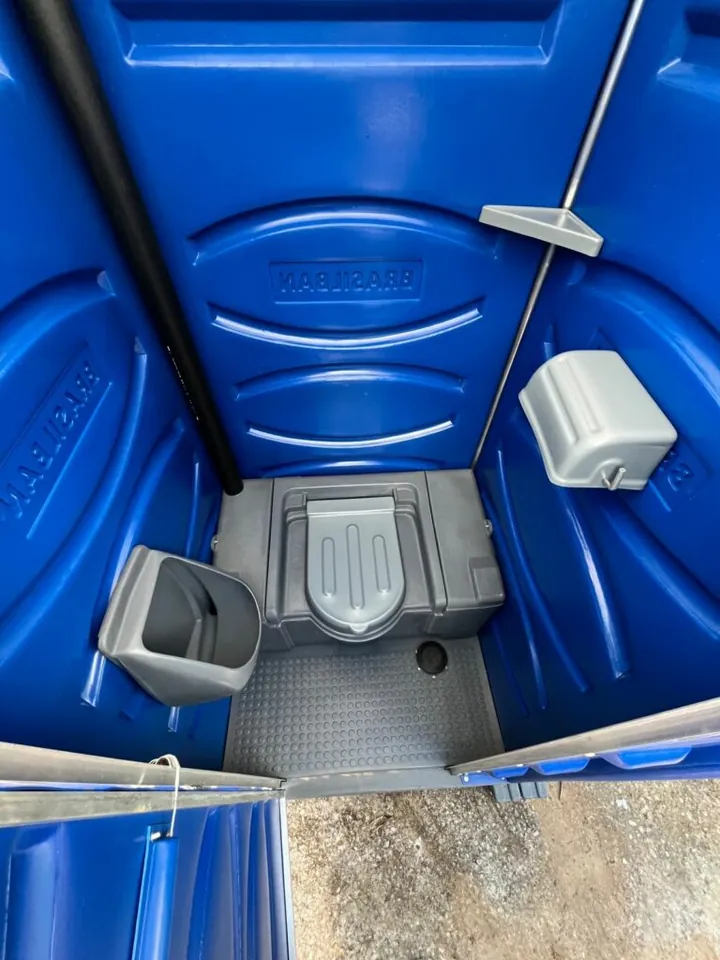 Interior do banheiro químico luxo com vaso sanitário, mictório, suporte de papel e acabamento em azul