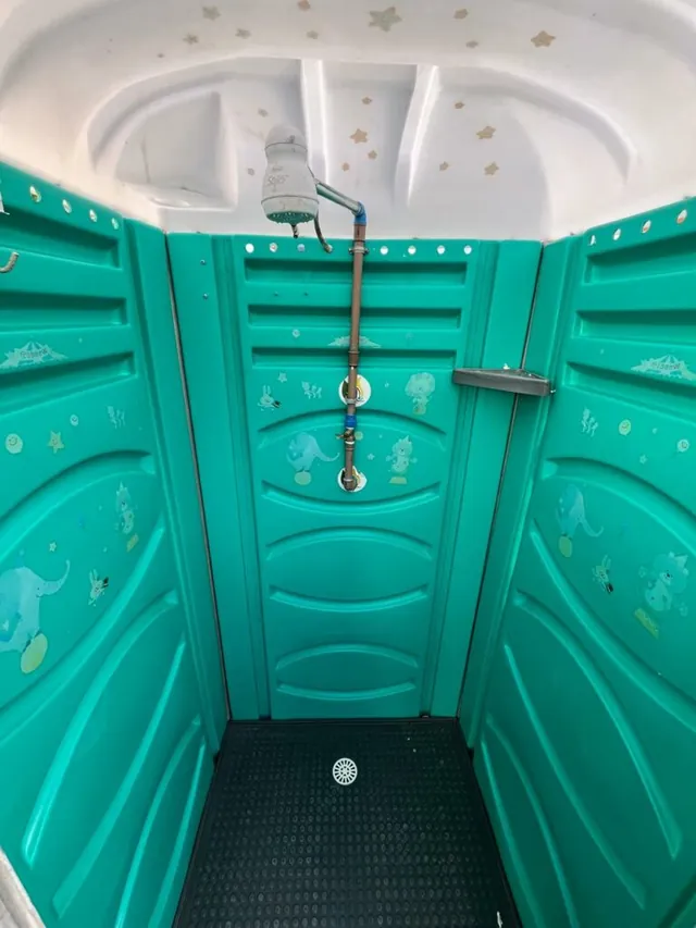 Interior da cabine de chuveiro da BrasilBan com chuveiro, ralo e piso antiderrapante